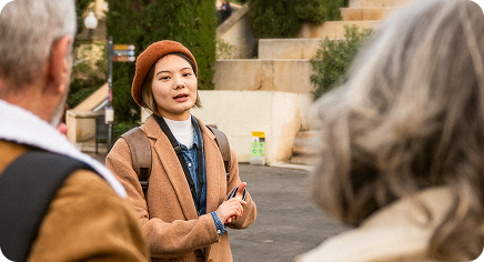 Tour guide speaking to a small group on a city street, gesturing while holding a phone.